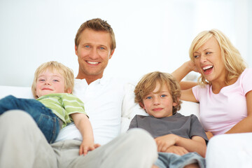 Obraz premium Theyre a young and vibrant family. Happy young family sitting on a sofa together at home.