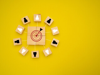 Wooden cubes with people icons focus on the goal over a yellow background