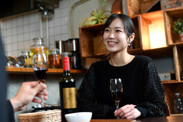 笑顔でお酒と食事を楽しむアジア人女性と男性（カップル）
