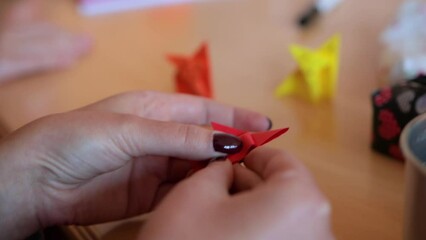 Close up detail shot of a skilled white caucasian woman folding and origami, creating origami fox, oriental traditional Japanese art on a wooden desktop - Powered by Adobe