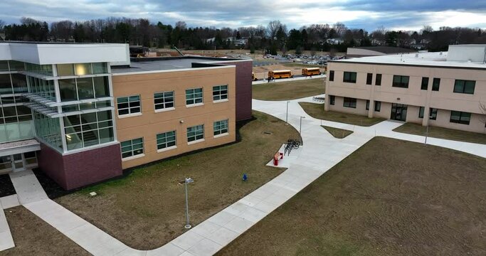 Modern school buildings at public education facility. School bus line up and drop off students. Morning aerial.