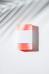 Bar of homemade soap with label on a white background. Mockup for design. Skincare cosmetic with shadows from palm leaves. Beauty concept for face body care