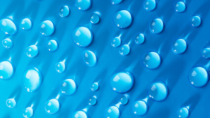 Water drops on blue background. Abstract drops of gel. Face serum cosmetics.