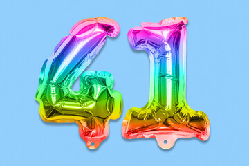 Rainbow foil balloon number, digit forty one on a blue background. Birthday greeting card with inscription 41. Top view. Numerical digit. Celebration event, template.