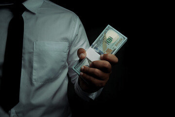 Businessman standing holding dollar on black background with space for text input. corruption,bribe.