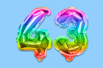 Rainbow foil balloon number, digit forty three on a blue background. Birthday greeting card with inscription 43. Top view. Numerical digit. Celebration event, template.