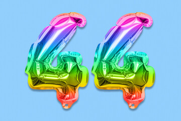 Rainbow foil balloon number, digit forty four on a blue background. Birthday greeting card with inscription 44. Top view. Numerical digit. Celebration event, template.