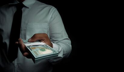 Businessman standing holding dollar on black background with space for text input. corruption,bribe.