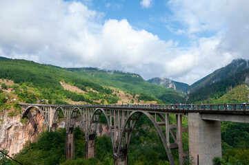a bridge over the river in the mountains on a sunny day