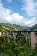 a bridge over the river in the mountains on a sunny day