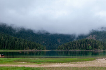 a foggy landscape of a mountain lake surrounded by a forest