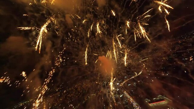 Epic Drone flight through glowing fireworks at dark night sky and illuminated city on the ground