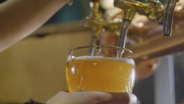 Close focus, slow motion shot of a girl hand pouring a draft beer, 4K footage, Croatia