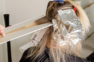 Set of hair dyeing process. Bleaching powder applying on hair and wrapping into the foil. Air Touch technique. Step 1