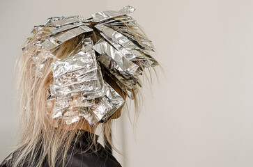 Foil on models hair. Bleaching or dyeing process. Beauty salon, fashionable hair coloring. Copy space