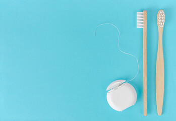 Bamboo toothbrush and dental floss on blue background. Dental care concept
