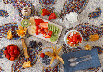 Low angle view of chia pudding dessert with summer berries, strawberries, kiwi and coconut slices, embellished with a mint sprig. No people.