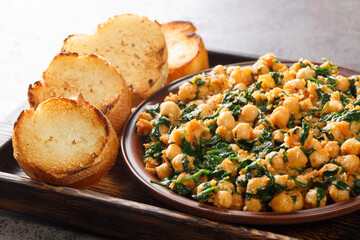 Spanish spinach and chickpeas served with toasts closeup in the plate on the table. Horizontal