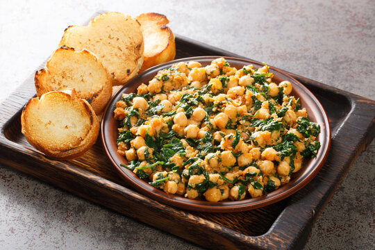 Spinach with chickpeas with spices, garlic and vinegar close-up in a bowl on a wooden board. horizontal