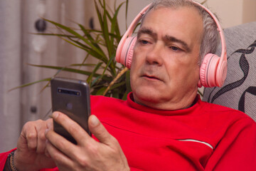 relaxed adult man with headphones and smartphone at home