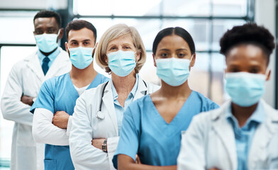 Working on the frontline with patients during the pandemic. Portrait of a group of medical practitioners wearing face masks while standing together in a hospital.