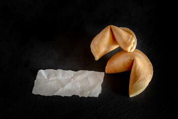 Fortune cookies with blank slip on dark background