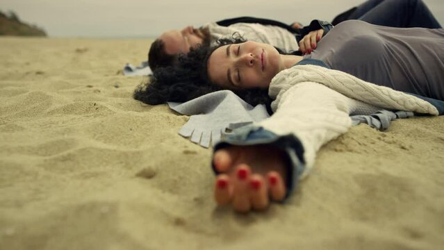 Hispanic couple chilling beach sand by sea. Relaxed lovers laying at seaside.