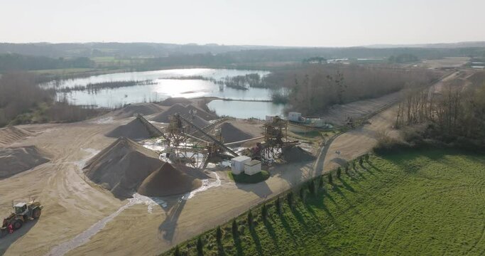 Aerial shot of machines and trucks working in a sand quarry, in France. Those are extracting and  filtering the sand.