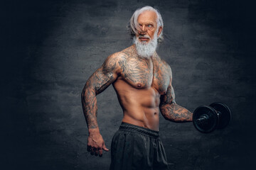 Bearded old man bodybuilder with tattoos holding dumbbell