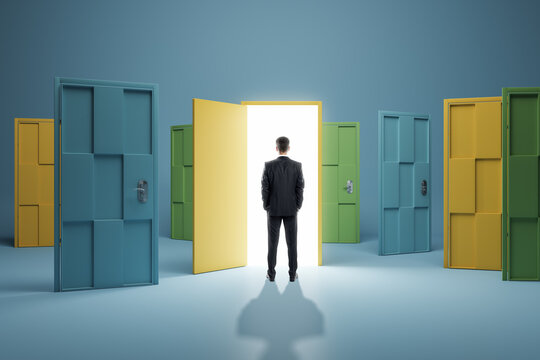 Man standing in front of abstract colorful puzzle door in interior. Future, choice, success, direction, opportunity and solution concept.