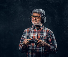 Indian elderly gamer with headphones holding joystick controller