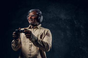 Indian elderly gamer with headphones holding joystick controller