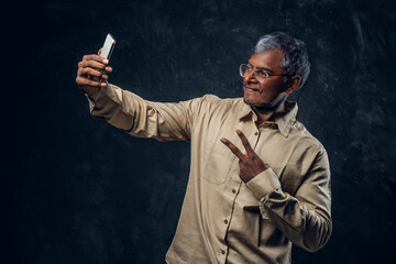 Cheerful elderly man taking shot using his cellphone