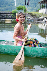 Portrait Beautiful girl paddles on a wooden canoe, Bali, Indonesia