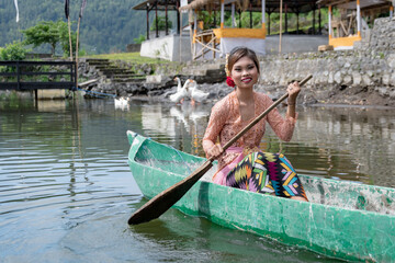 Portrait Beautiful girl paddles on a wooden canoe, Bali, Indonesia