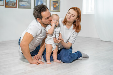 family in the studio or at home crawling on the floor with a baby. mom, dad, son play together