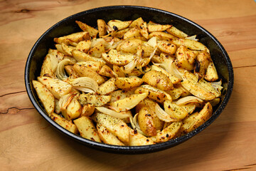 roasted potatoes in a frying pan, cooked food, delicious crust, one object on a wooden background