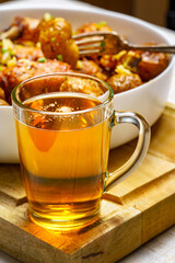 tasty lunch in rural style, healthy food - glass of beer, fried chicken meat and unpeeled roasted potatoes, chopped leeks, cooked food on a white wooden boards