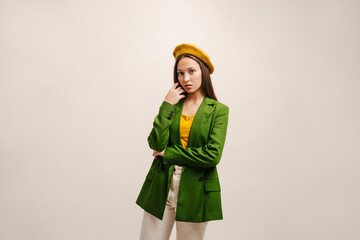 Studio shot of pensive young caucasian girl looking at camera while touching face. Brunette woman...