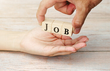 Hand of a business man handing a wooden block with a job message to a female applicant.                    