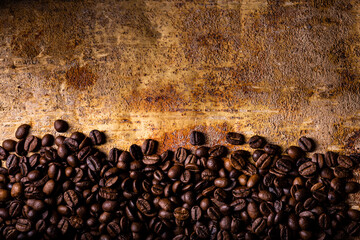 In the foreground, from above, on the textured brown rustic background, roasted coffee beans. Blank space for your text
