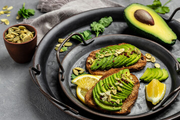 Fresh green Avocado sandwich rye bread, pumpkin seeds, salt and pepper. Vegetarian food. Plant-based diet. Clean eating. Top view. Copy space
