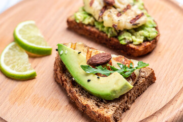 Grilled Halloumi cheese, avocado guacamole, arugula on roasted bread. Food recipe background. Close up
