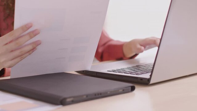At home, an Asian designer works on a desk with a laptop, searching for jobs and paperwork.Designer web development website template design user ui application on paper.