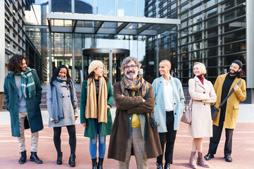 Happy team of multi ethnic professionals standing and smiling outside the business company workplace