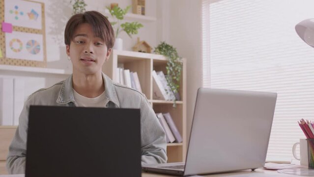 Asian Designer man work from home and communicate with the design team over the internet. On a teblet,women are having a video conference call.