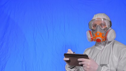 Scientist virologist in respirator makes write in an tablet computer with stylus. Man wearing...