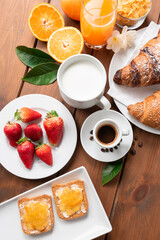 Colazione europea in tavola - caffè espresso, latte, frutta fresca e croissants 