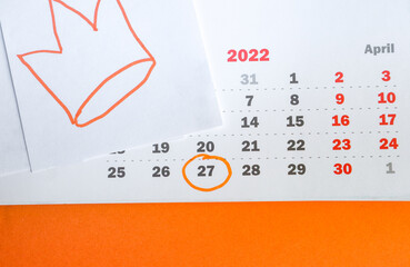Close-up of a paper calendar on April 27, 2022 with an orange background and a hand-drawn crown in the traditional colors of the King's Day celebration in the Netherlands