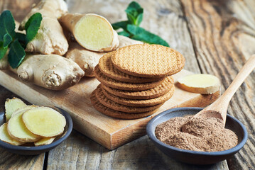 Ginger biscuits served with ginger root and grounded ginger powder. Fresh ginger biscuits served with ginger roots and grounded ginger powder on wooden table.